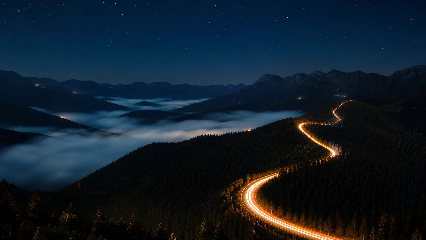 A mountain road traced by warm light at night