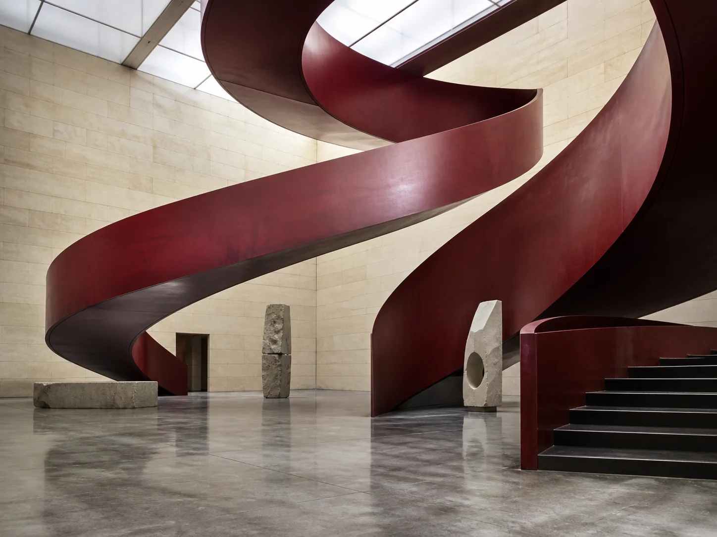 Dark red spiral staircase inside a contemporary gallery